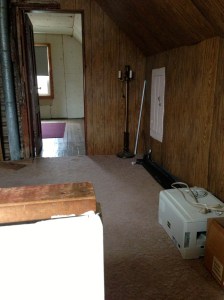 Peeking over the half wall at the top of the stairs, you can see the paneled room (and some of the crap left behind) into the second room.